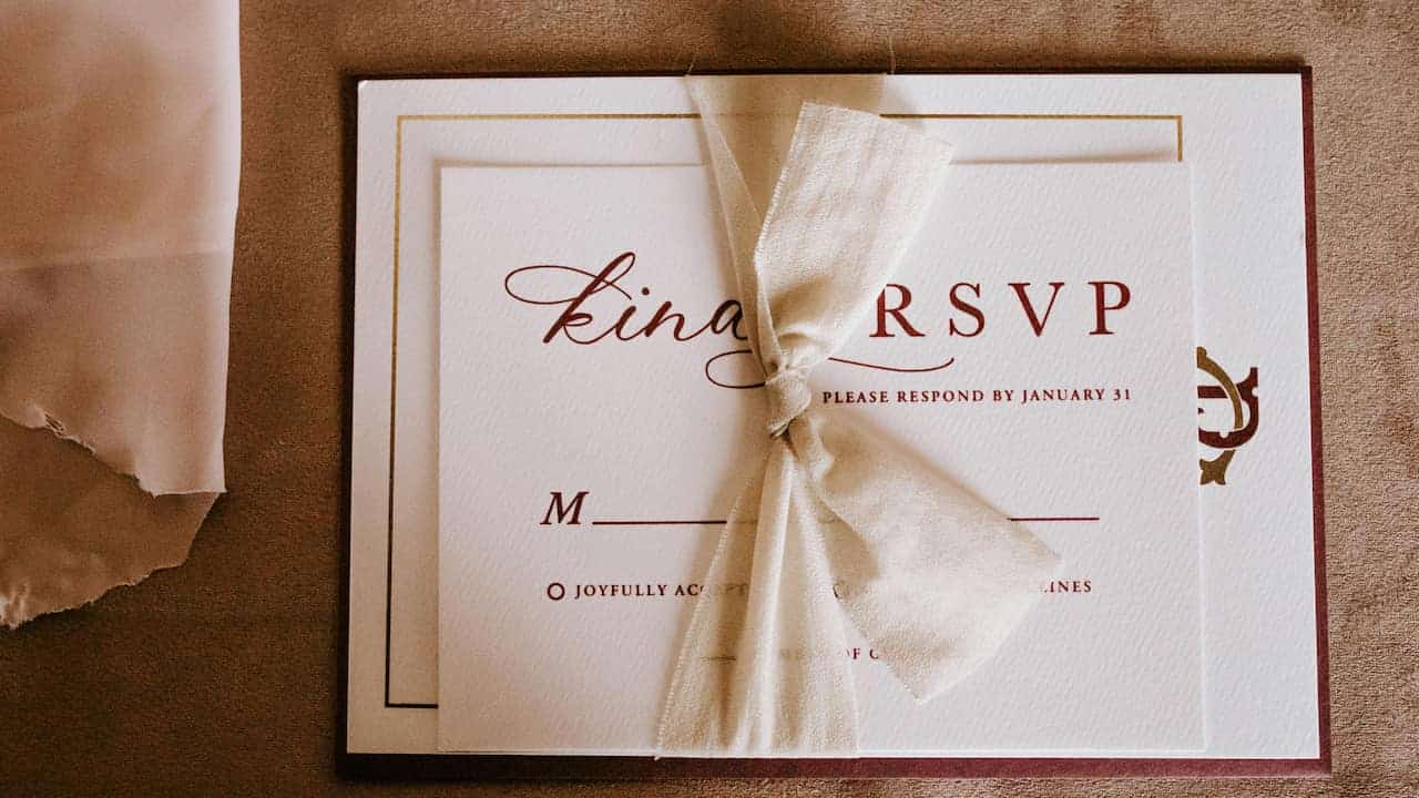 Wedding invitation card featuring the letters RSVP prominently, decorated with pink floral accents, includes a clear "Respond by" date section for guests to confirm attendance