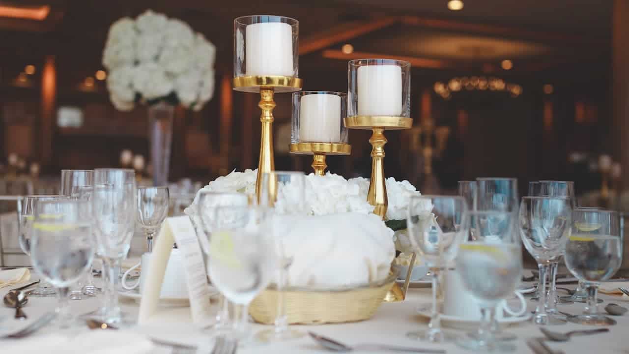 Elegant table with white flower centerpiece, gold candelabras with white candles, wine glasses, and formal place settings