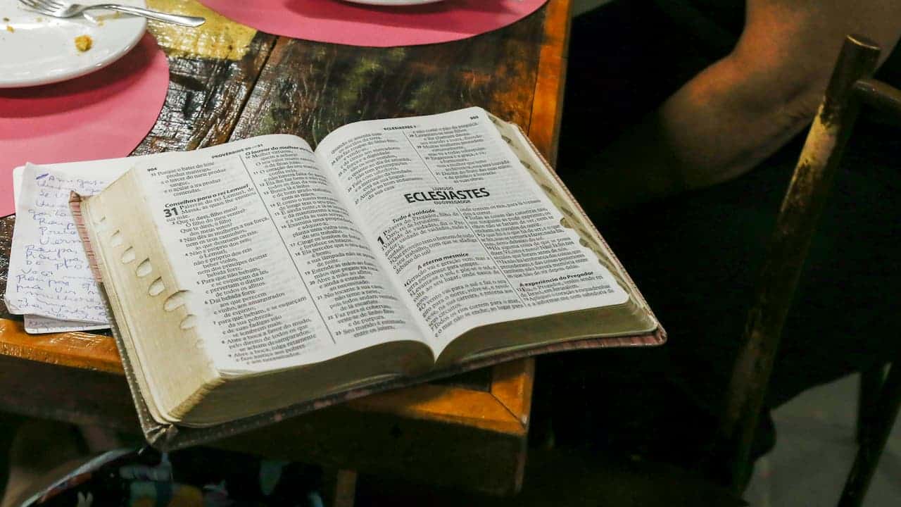 An open family Bible with handwritten notes and highlights on the pages, resting on a wooden surface, showing signs of frequent use and personal reflection