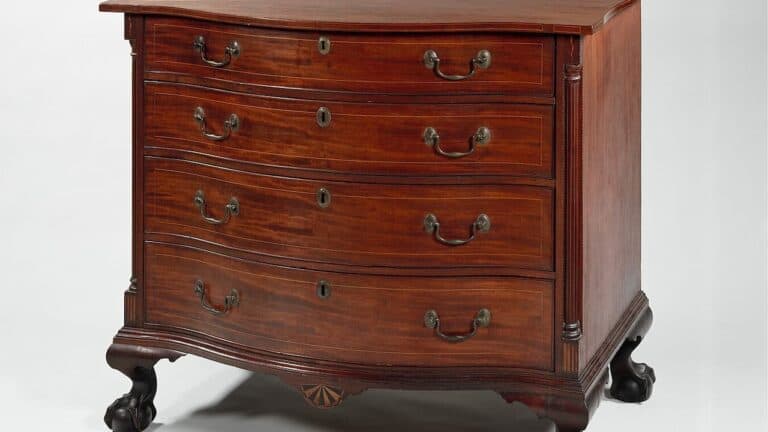 Federal style mahogany chest of drawers with four drawers, brass handles, decorative columns, and curved legs on white background