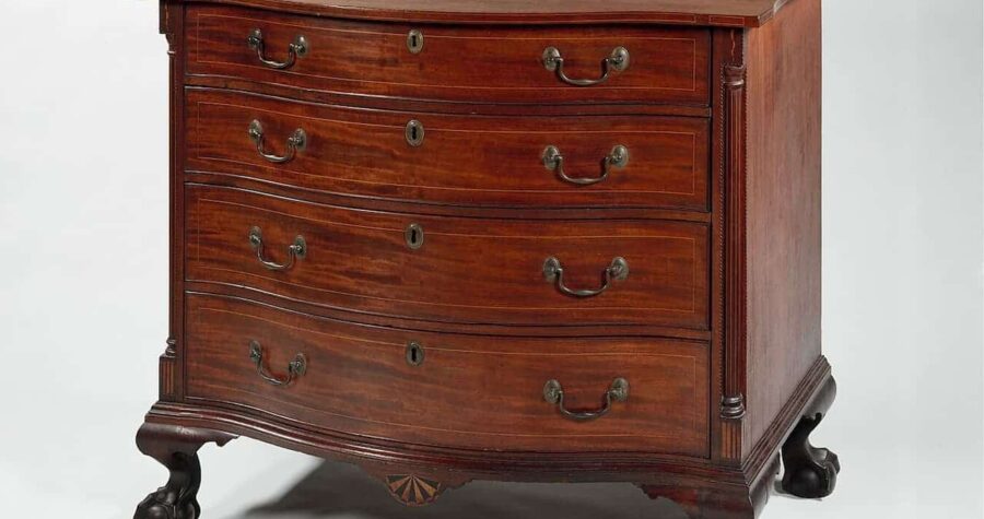 Federal style mahogany chest of drawers with four drawers, brass handles, decorative columns, and curved legs on white background
