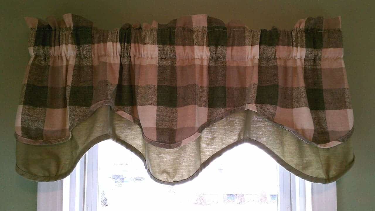 Boxy window valance with pink and brown checkered pattern hanging from rod over white-framed window
