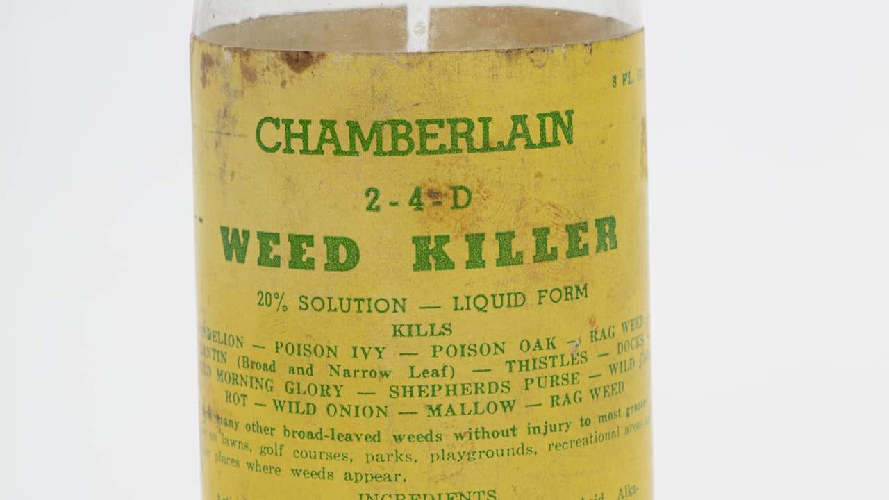 Plastic bottle labeled Chamberlain 2,4-D Weed Killer, featuring safety warnings and usage instructions