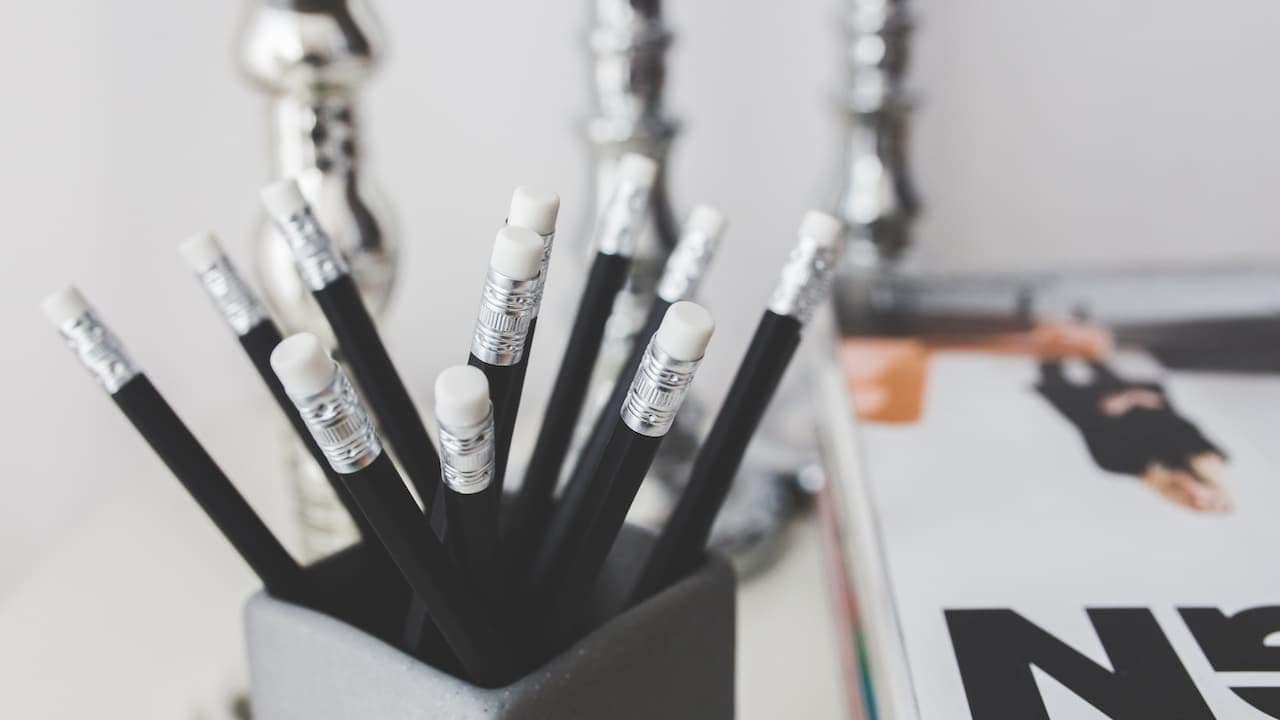 Black pencils with white erasers in a grey holder