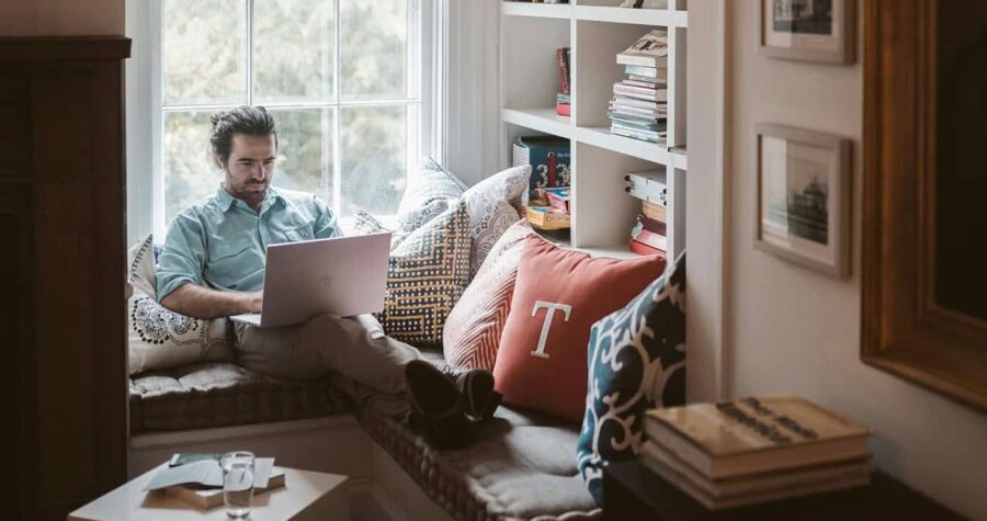 Man working on laptop near window seat area
