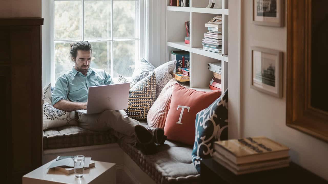 Man working on laptop near window seat area