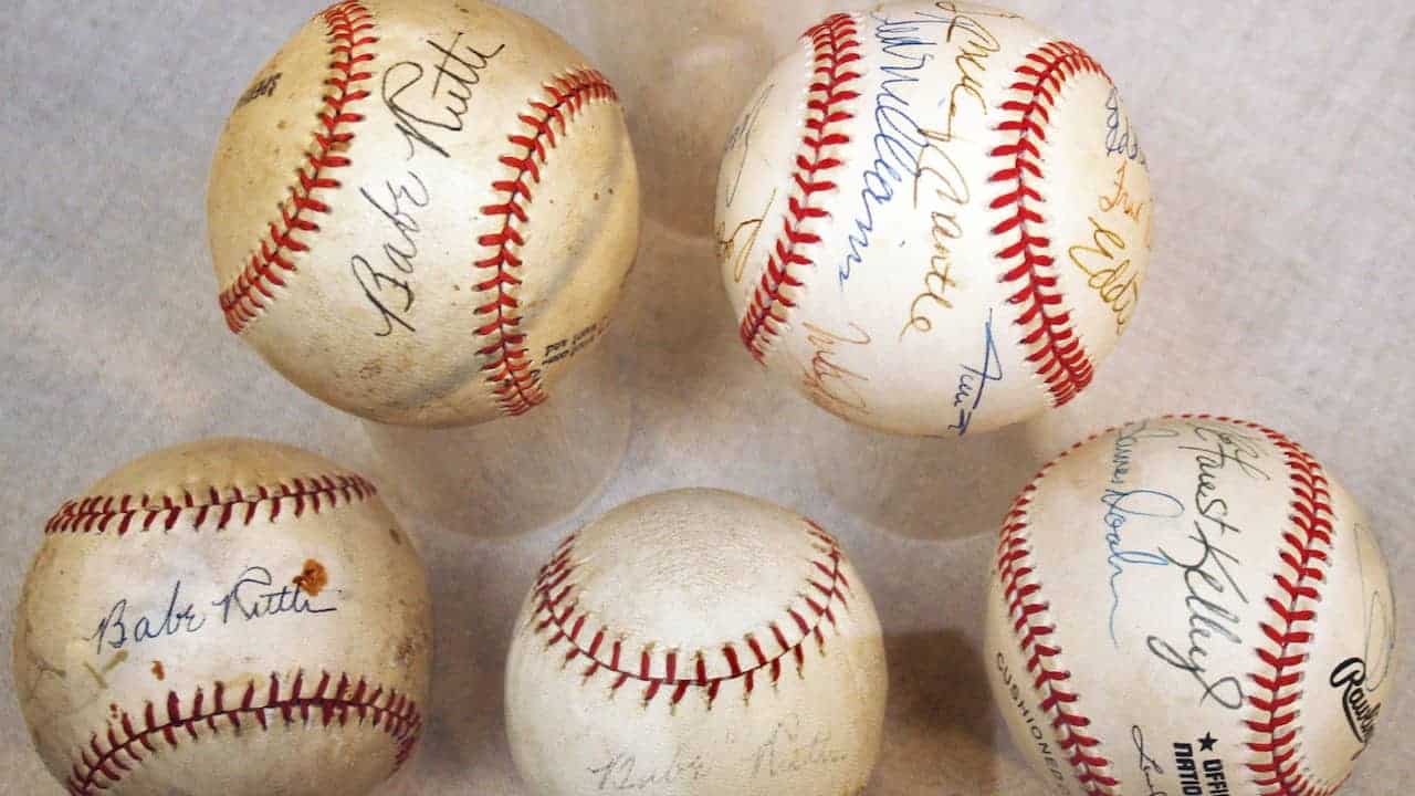Five autographed baseballs on display, including multiple signed by Babe Ruth