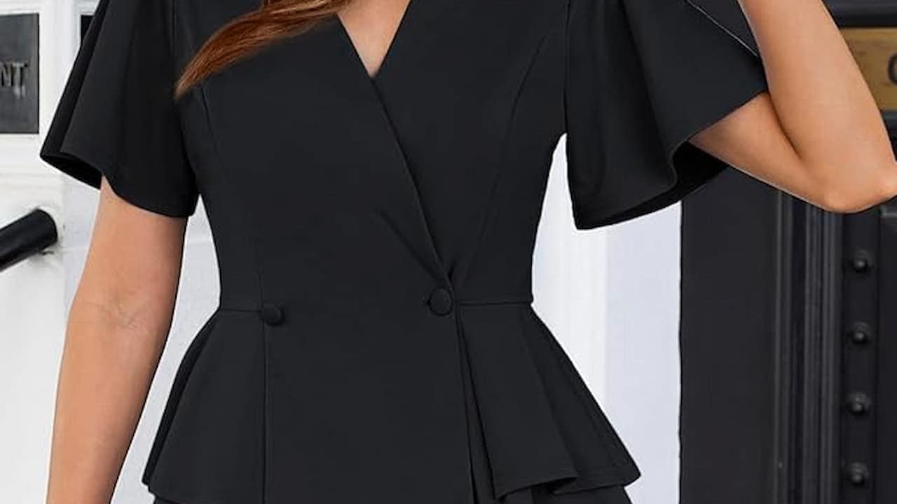 Woman wearing black wrap-style dress with short sleeves, tie waist, V-neckline, fitted silhouette, indoor setting