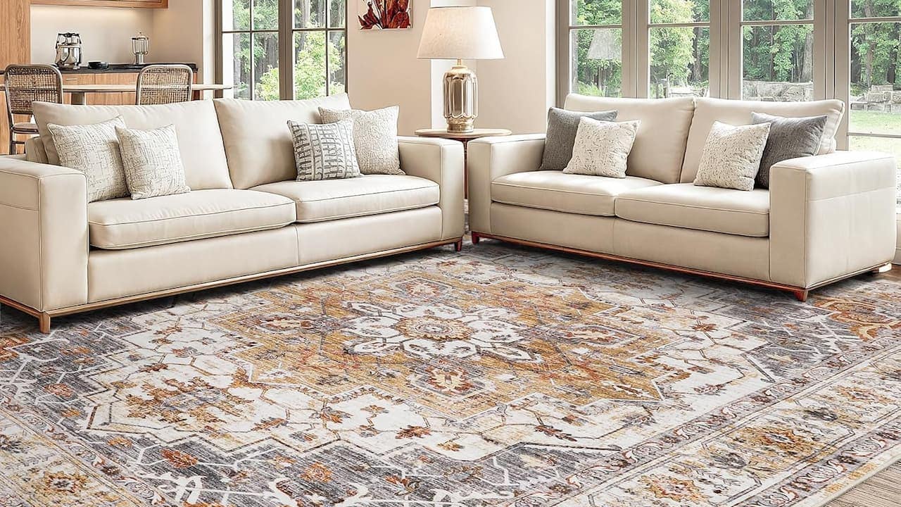 Light-colored sectional sofa with throw pillows positioned on patterned area rug in bright living room