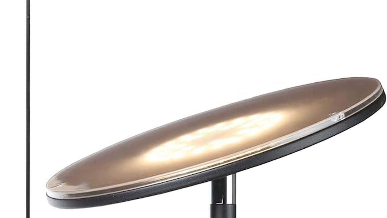 Close-up of curved metallic surface, possibly part of a lamp or fixture with warm lighting reflection