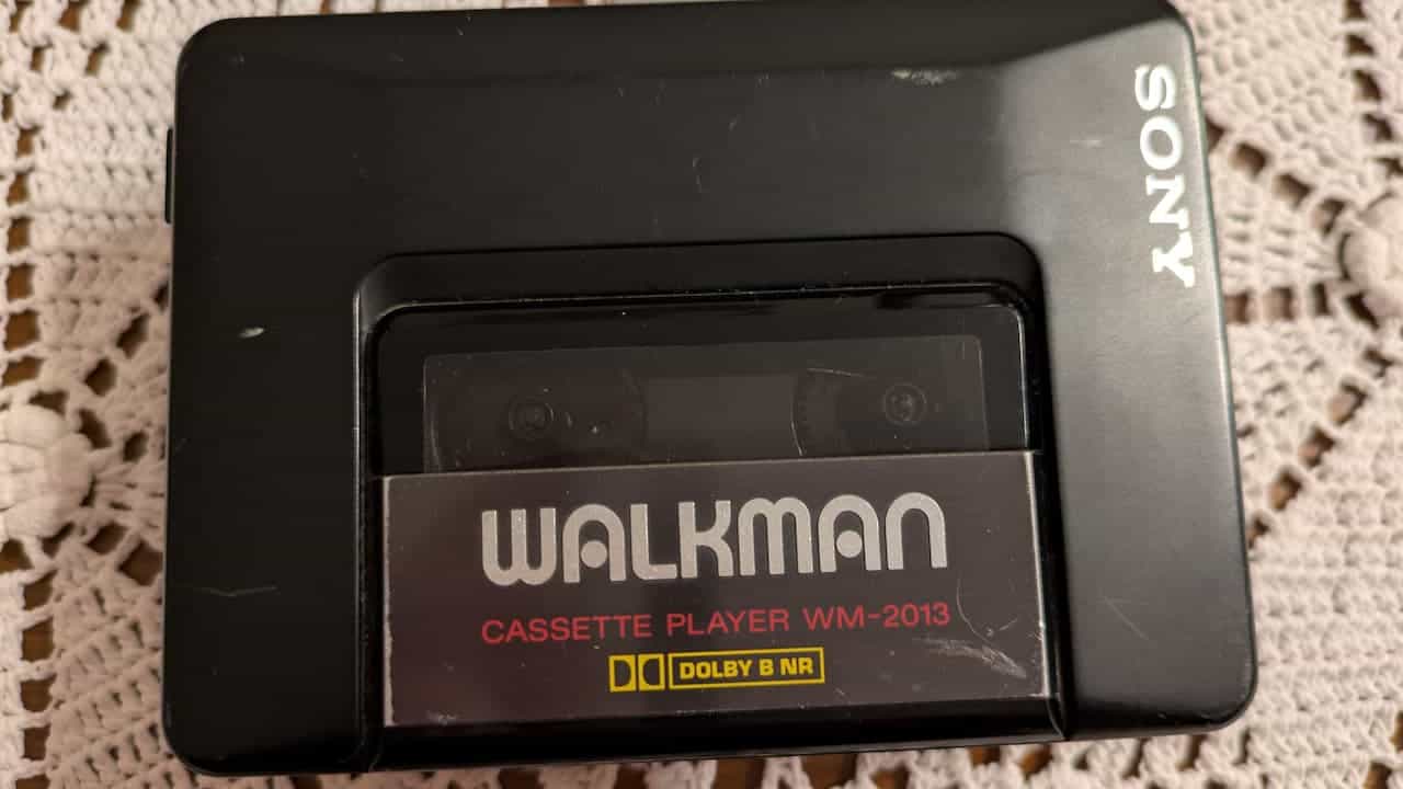 Black Sony Walkman cassette player with visible tape inside, model WM-2013, placed on a crochet surface