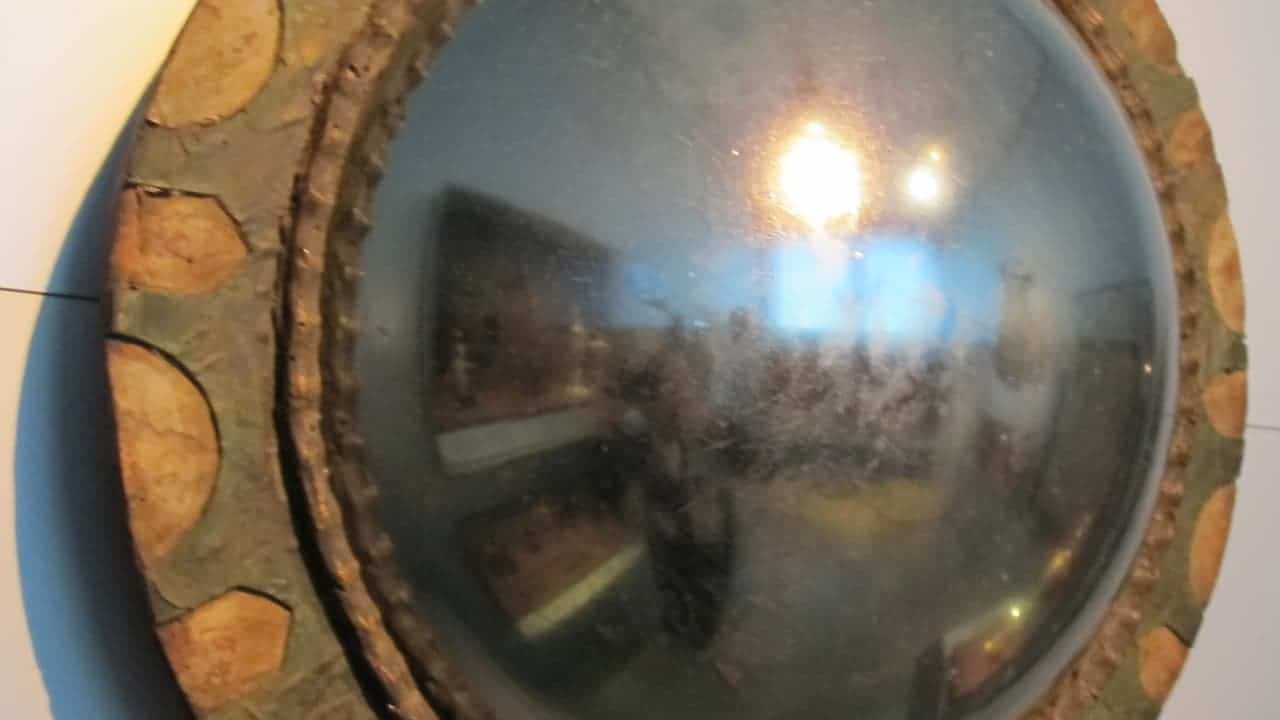 Federal period convex mirror with ornate gilded frame featuring circular decorative elements and reflective convex glass surface