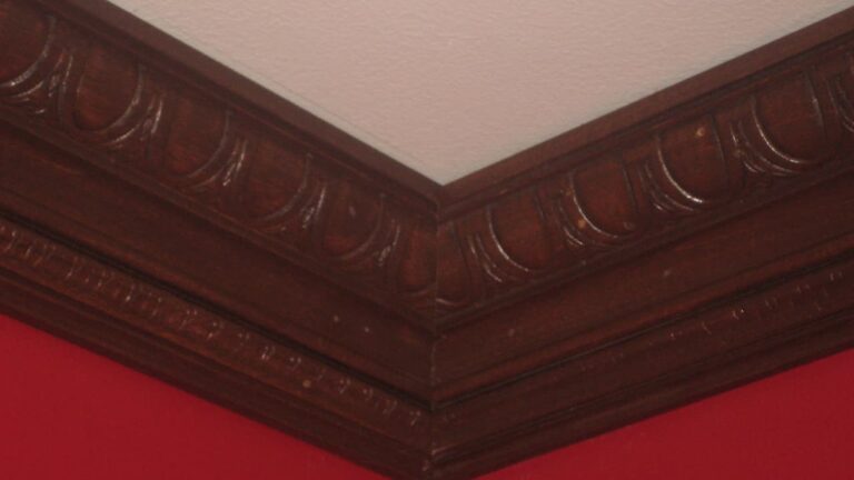 Decorative dark wood crown molding along the edge of a red wall and white ceiling corner