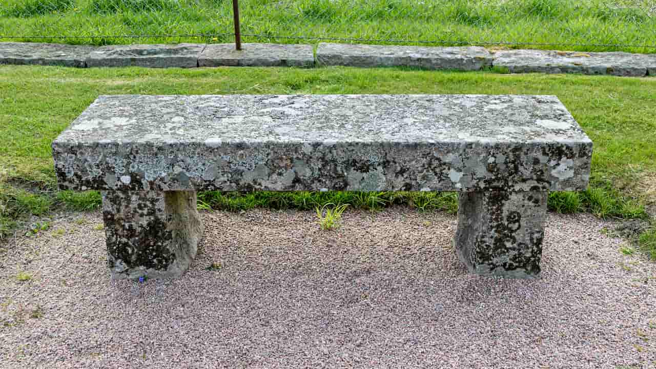 Stone bench with a flat seat and solid base, placed in an outdoor setting