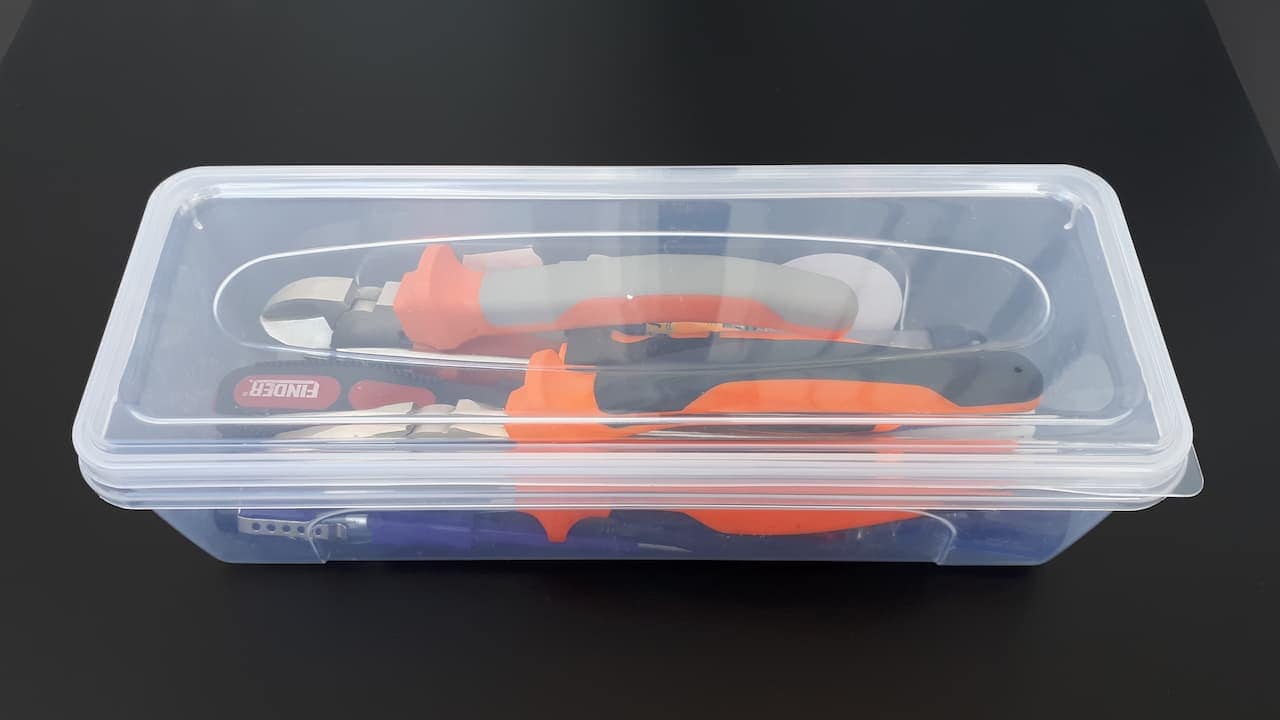 Transparent plastic box with assorted tools inside, including screwdrivers, pliers, and small hardware