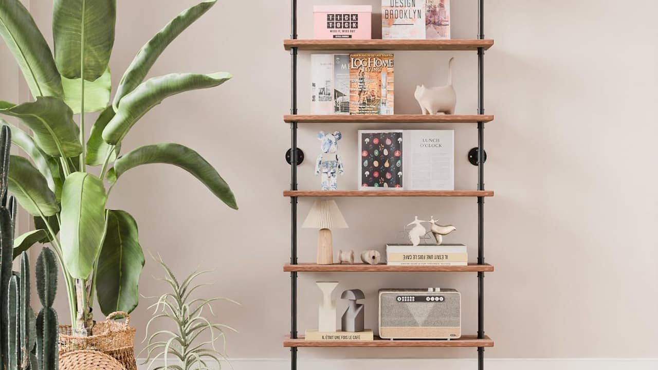 Wooden bookshelf or display unit with multiple shelves holding books, decorative objects, and storage baskets against white wall