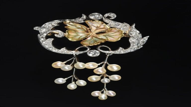 Ornate vintage brooch with diamond-encrusted scrollwork frame, central abalone shell flower motif, and cascading pearl drop dangles