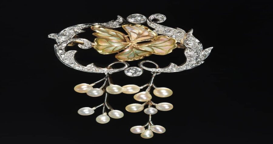 Ornate vintage brooch with diamond-encrusted scrollwork frame, central abalone shell flower motif, and cascading pearl drop dangles