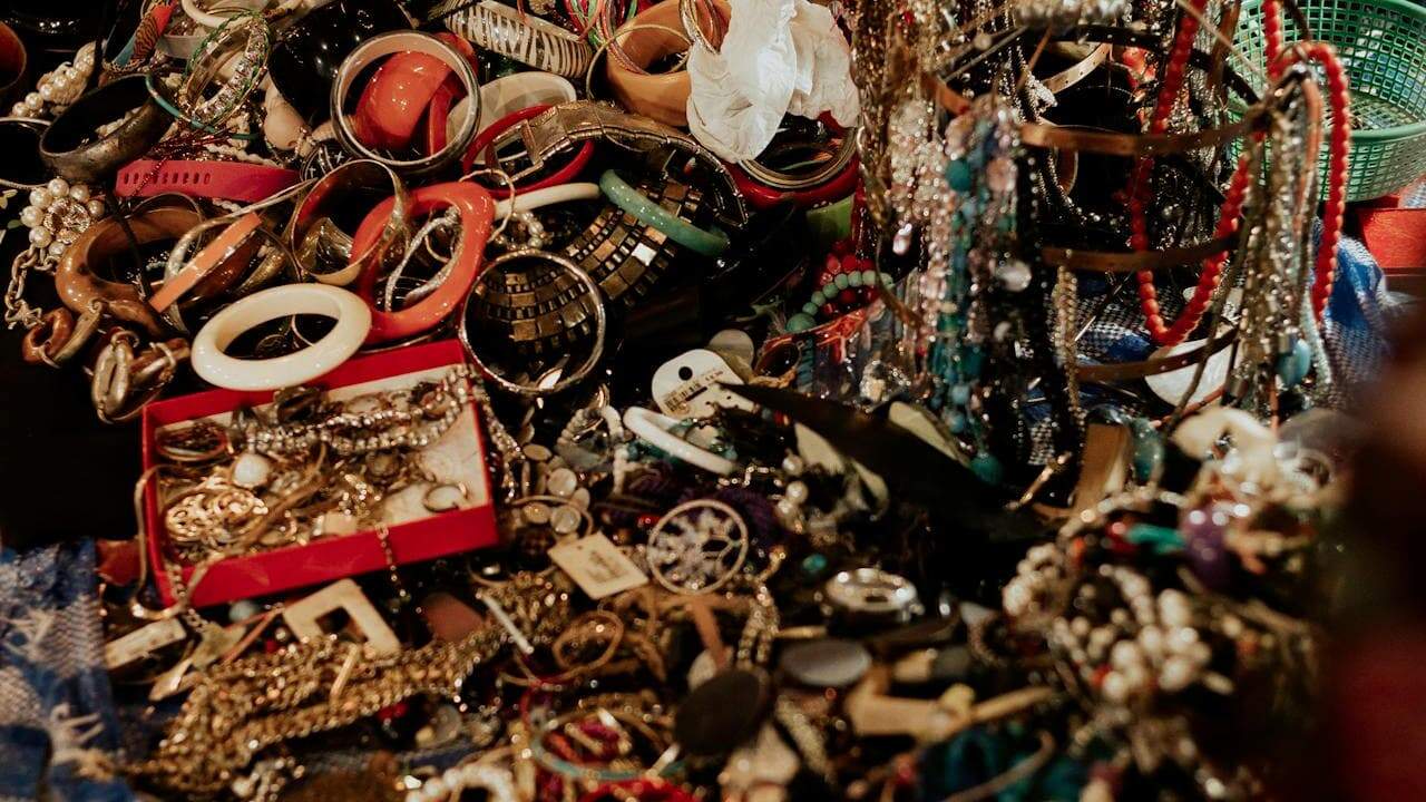 Chaotic pile of vintage costume jewelry including necklaces, bracelets, brooches, pearls, and accessories creating overwhelming visual clutter and disorganization