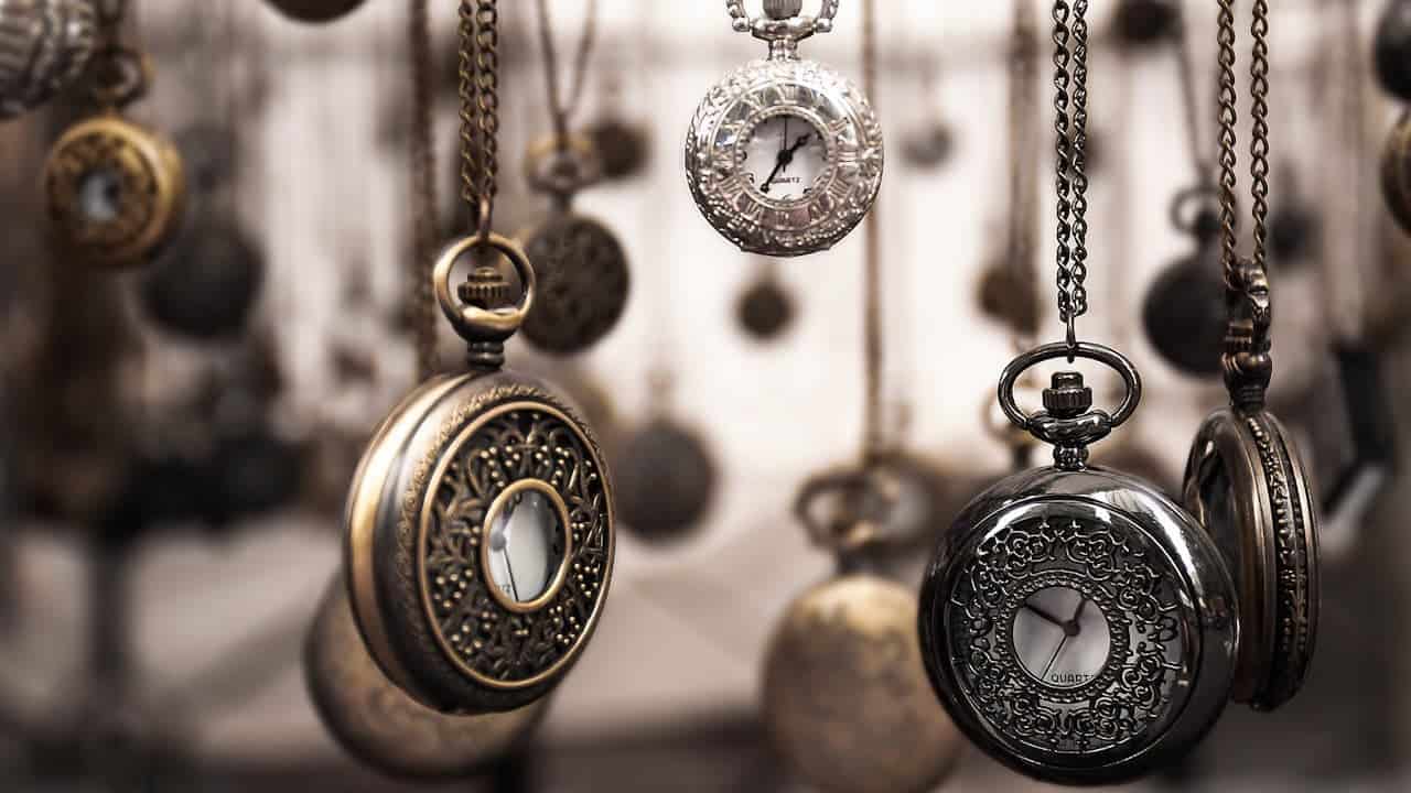 Collection of ornate pocket watches hanging on chains with decorative engravings and vintage-style designs in various metallic finishes
