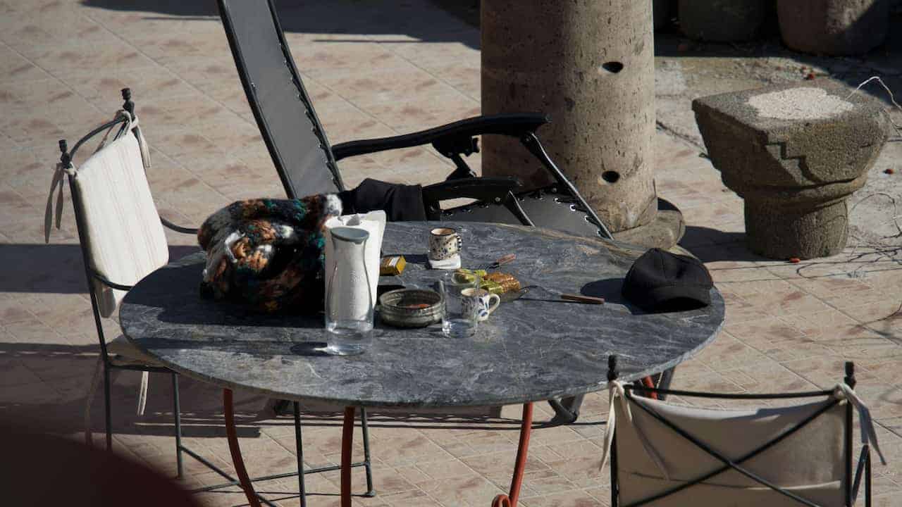 Dinner table with chairs arranged around it on a patio slab, outdoor setting