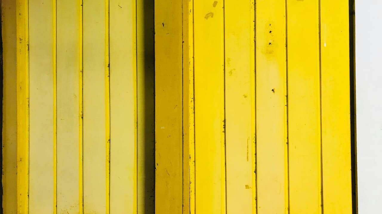 Vertical faux wood panels painted in various shades of yellow, with narrow grooves and visible marks