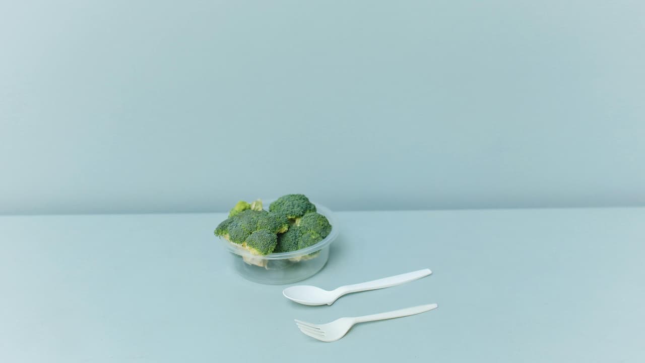 Two single-use plastic forks, lightweight, disposable design, smooth or slightly textured surface, often white