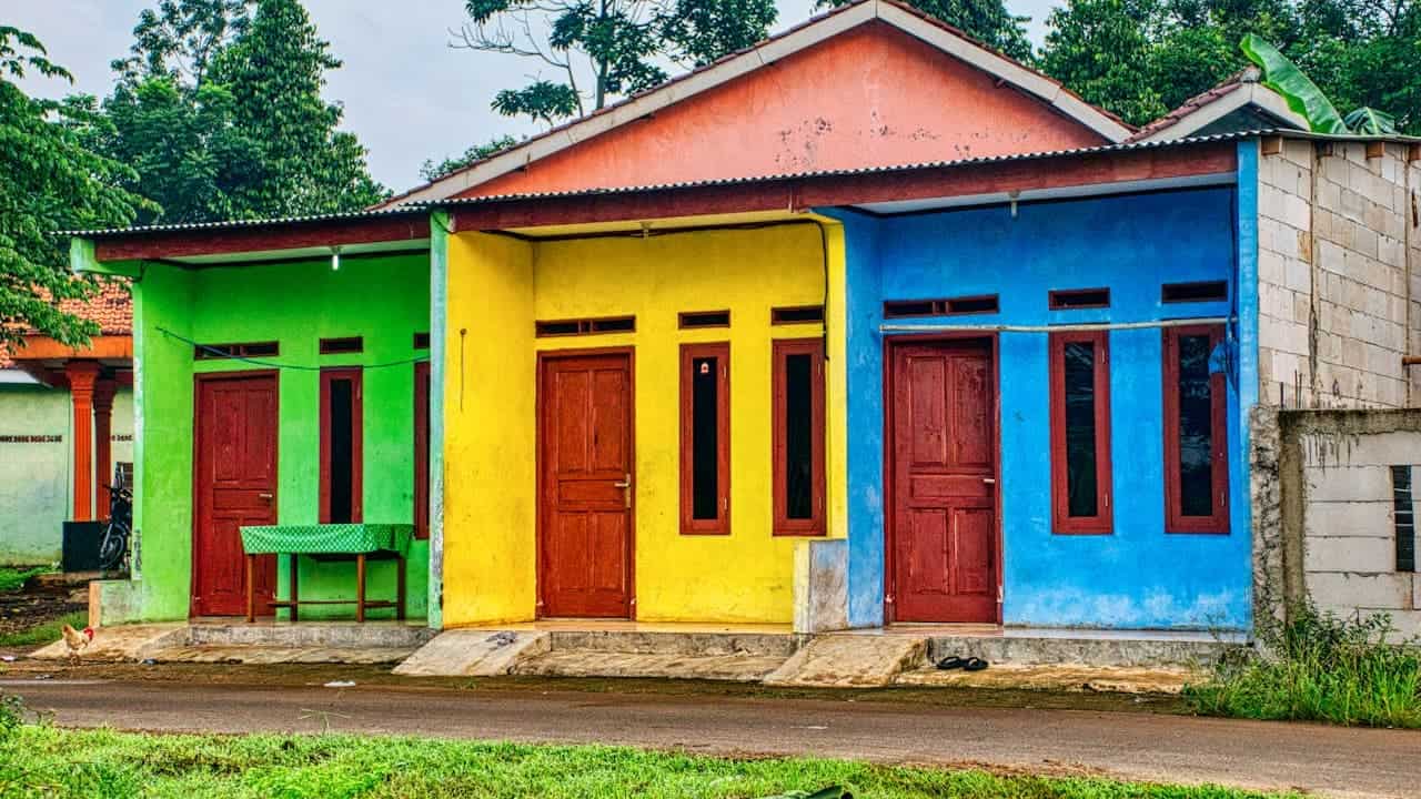 Row of small houses painted in bright contrasting colors - green, yellow, and blue with red doors and windows