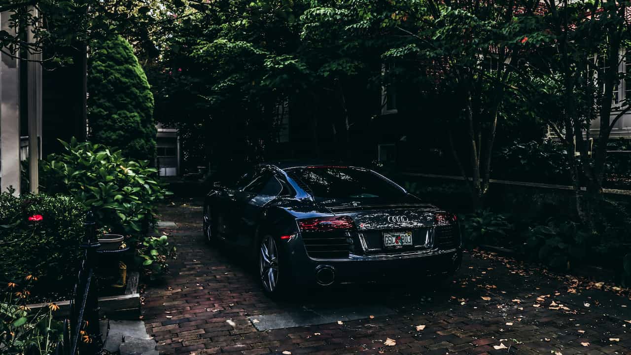 Luxury car parked in a residential driveway, sleek design, clean pavement, surrounded by modern home elements
