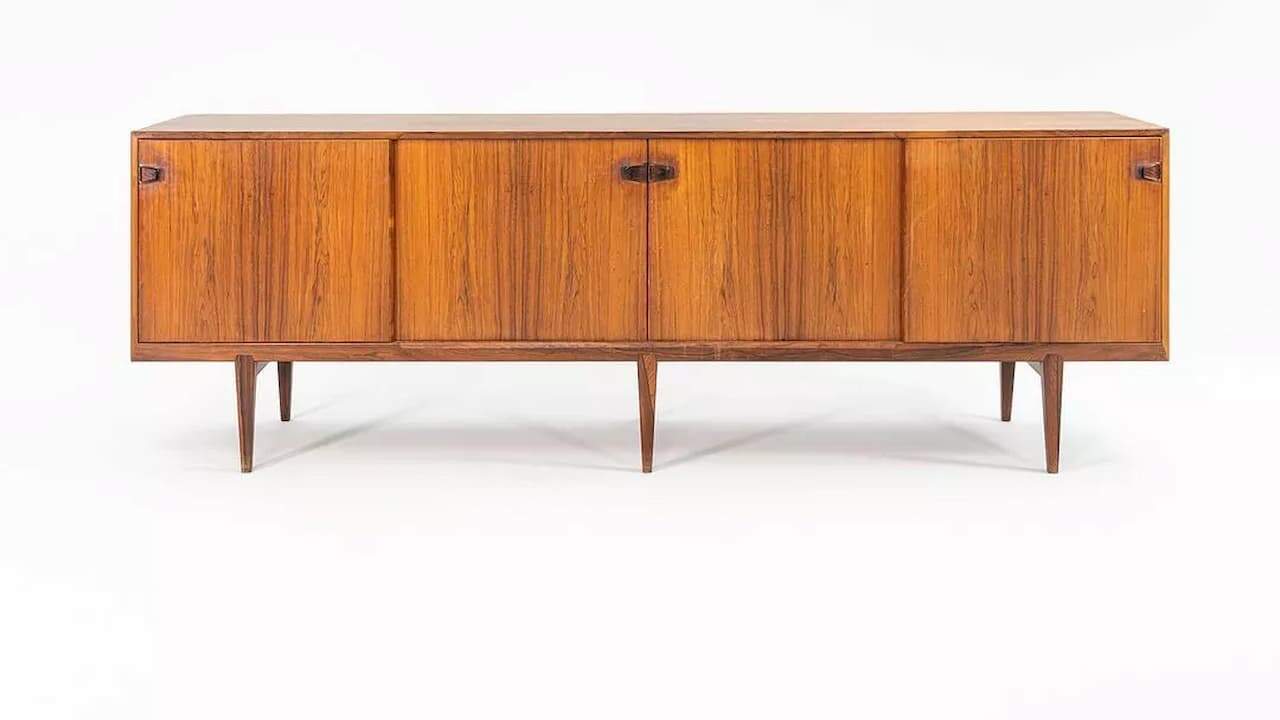 Vintage Danish modern rosewood buffet with four cabinet doors, sleek horizontal design, and tapered legs on white background