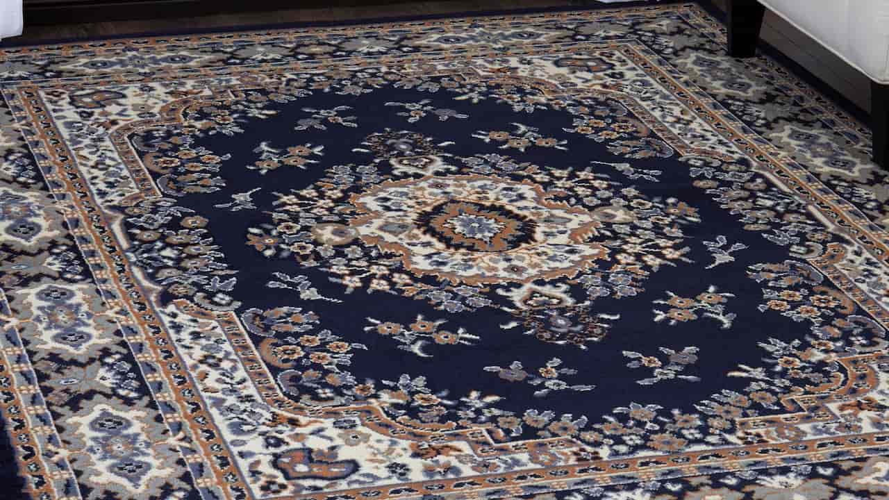 A traditional Persian-style area rug with a navy blue background, intricate floral and medallion patterns in cream, beige, and rust tones