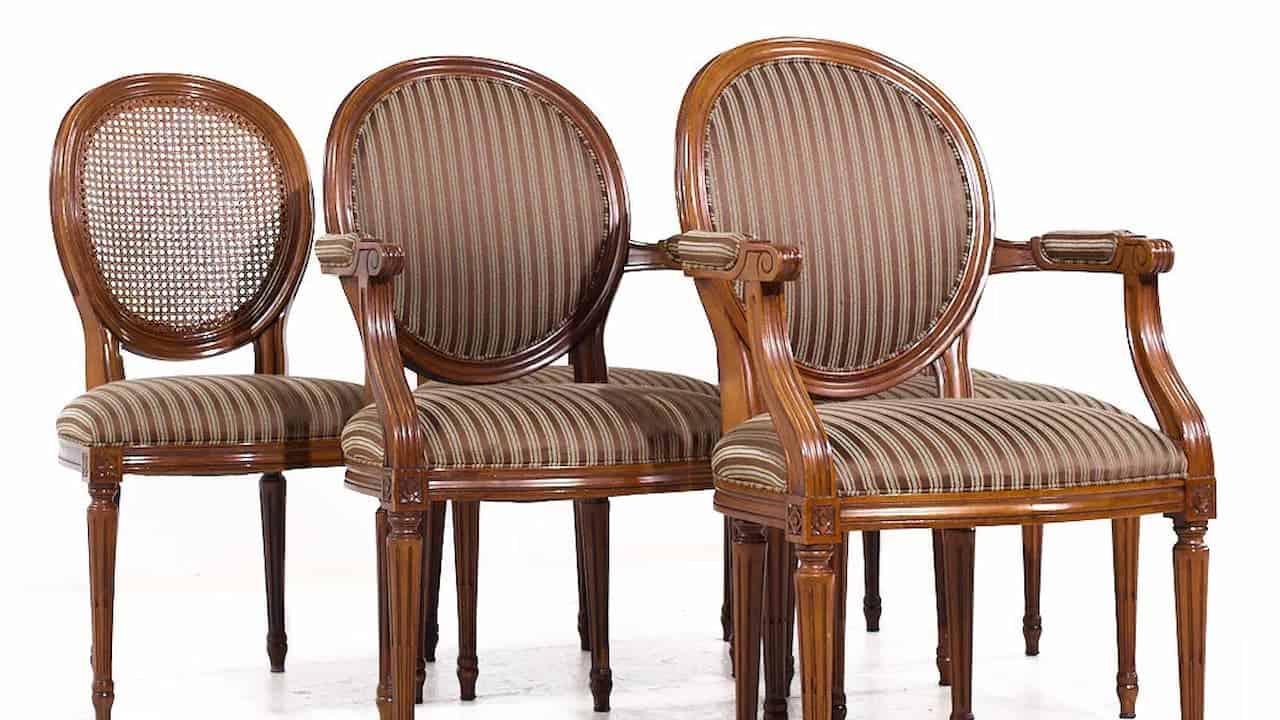 Three Hepplewhite mahogany dining chairs with round backs, striped upholstery, and carved wooden frames on white background