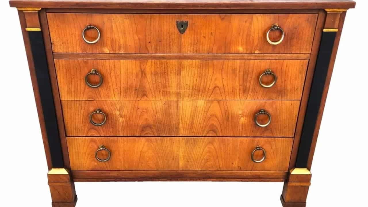 Art Deco walnut chest of drawers with four drawers, brass ring handles, black and gold column details, clean geometric design