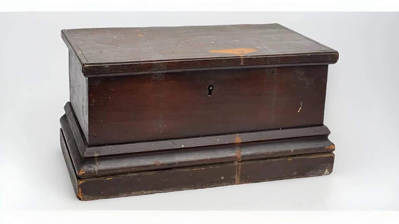 Early American pine blanket chest with dark finish, keyhole lock, and worn paint showing age and use