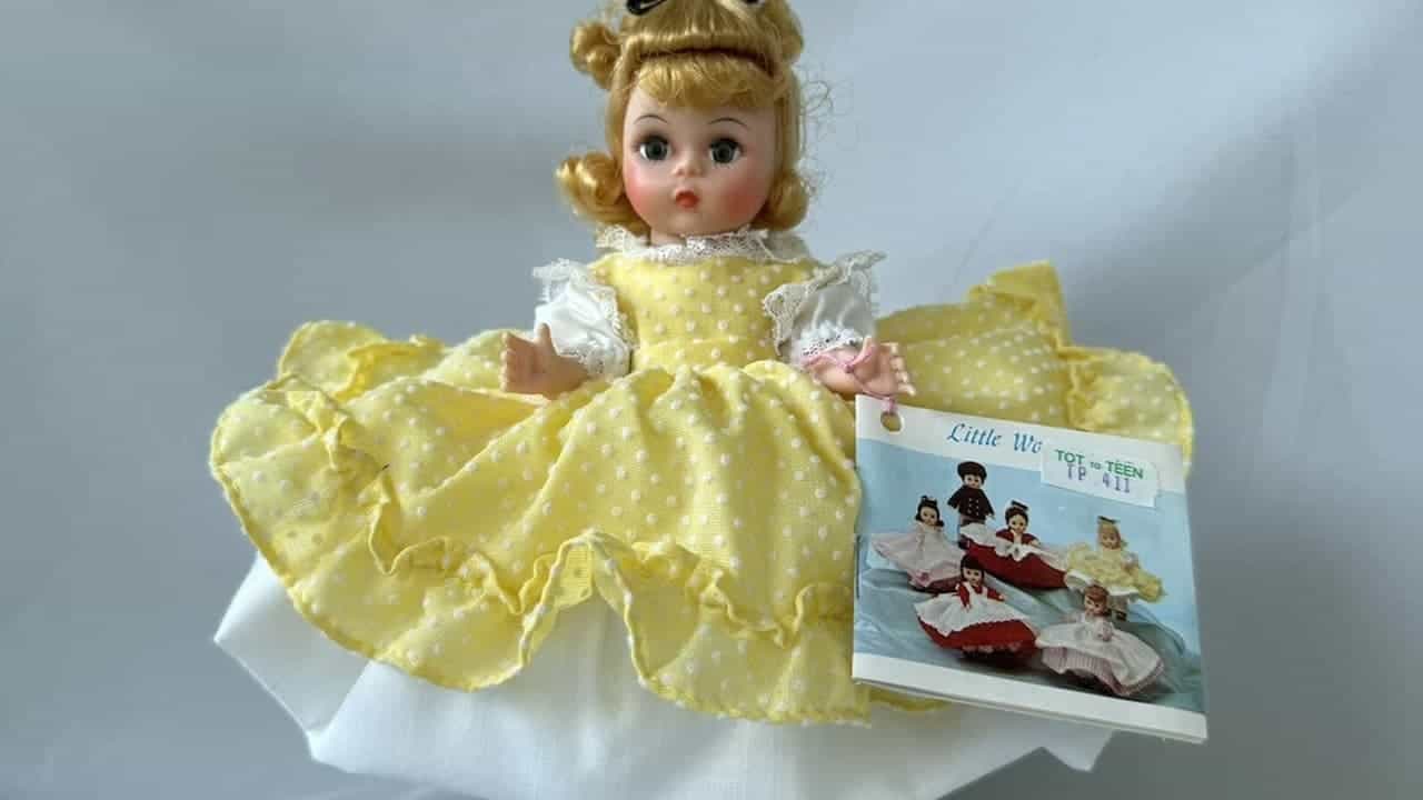 1970s collectible doll with blonde hair in yellow polka dot dress displayed with "Little Women" product booklet