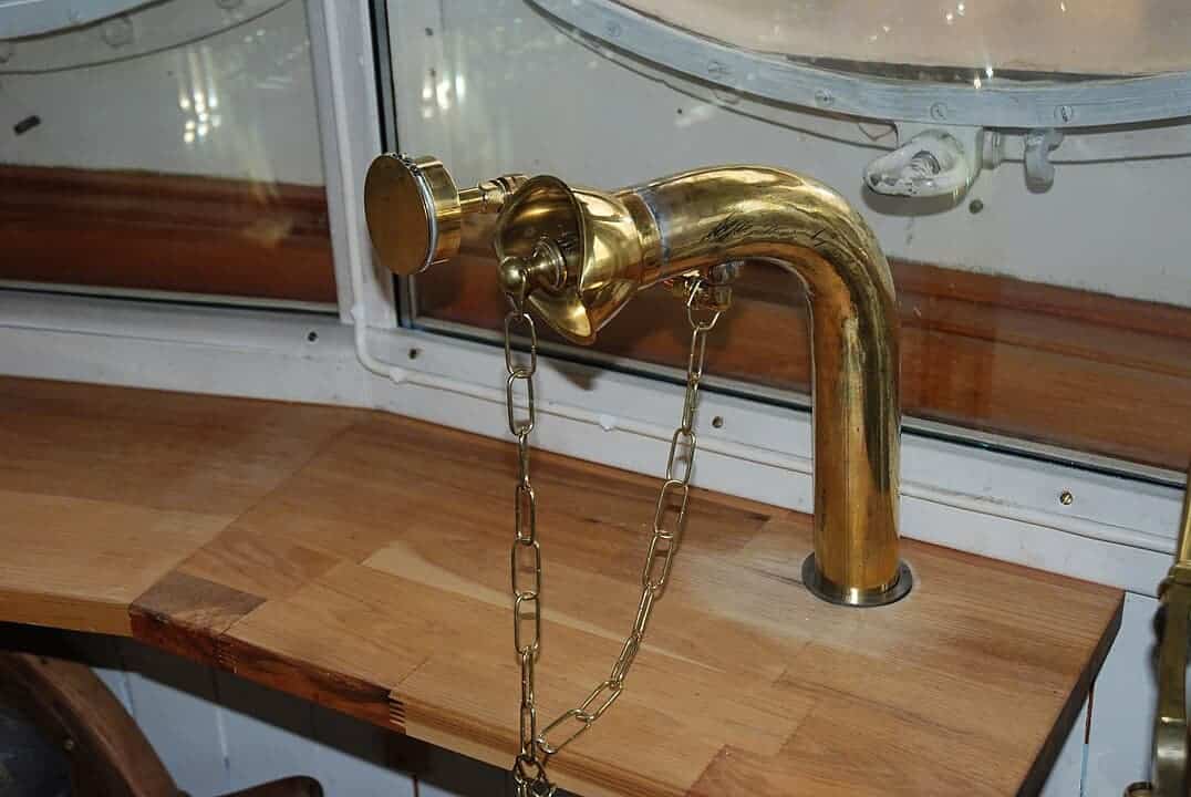 Modern open-plan living space with gray sofa, dining table, purple chairs, contemporary light fixture, wood floors, kitchen in background