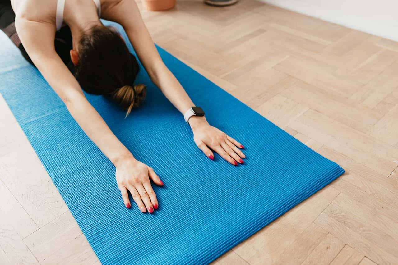 Slim sportswoman stretching on mat in Child Pose
