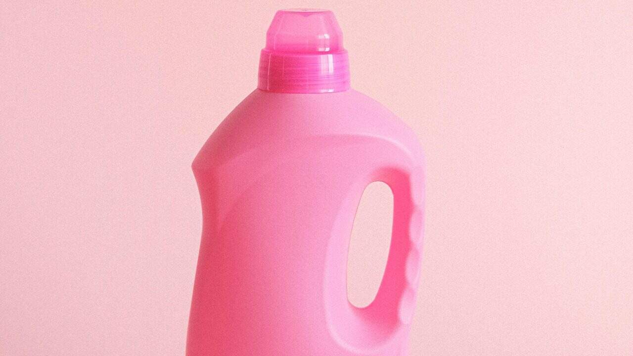Simple pink plastic detergent bottle on a pastel background, perfect for hygiene and cleaning concepts.