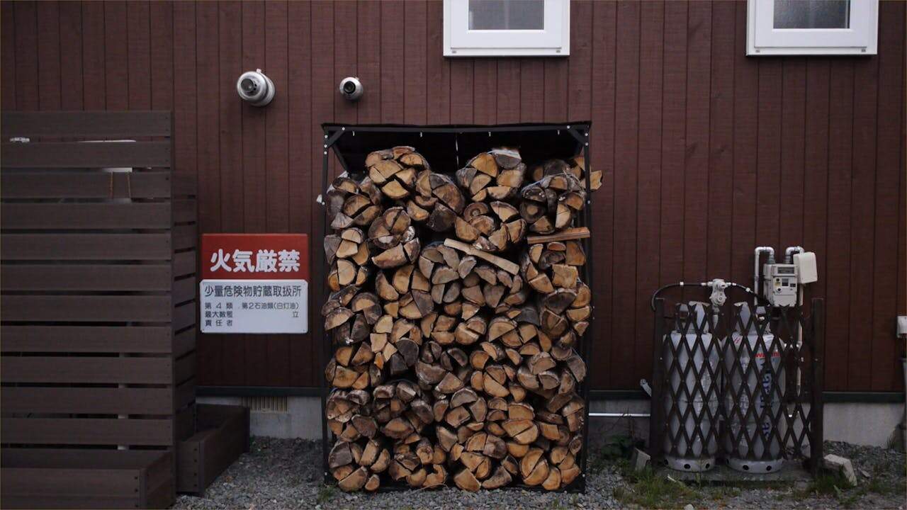 Stack of Firewood Next to Gas Cylinders at the Back of the Building