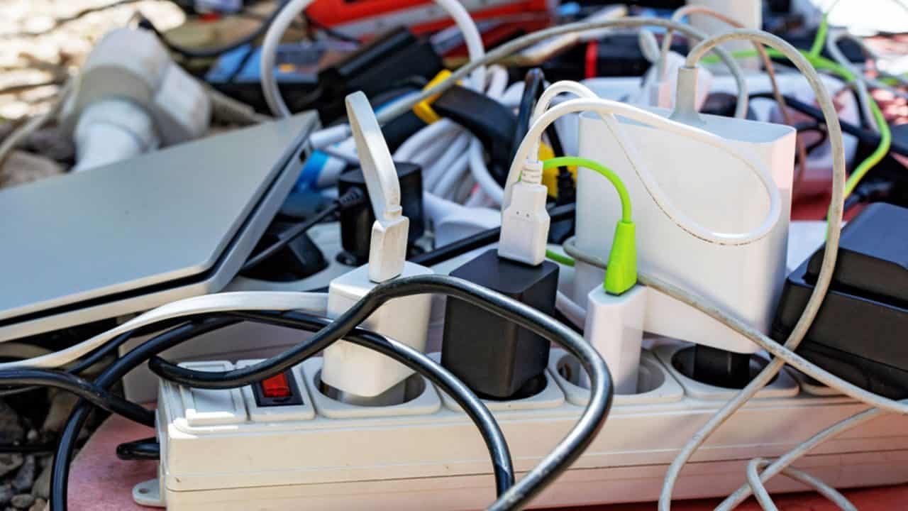 Overloaded power strip, multiple plugs and chargers, tangled cords, USB connectors, adapter blocks, cable clutter