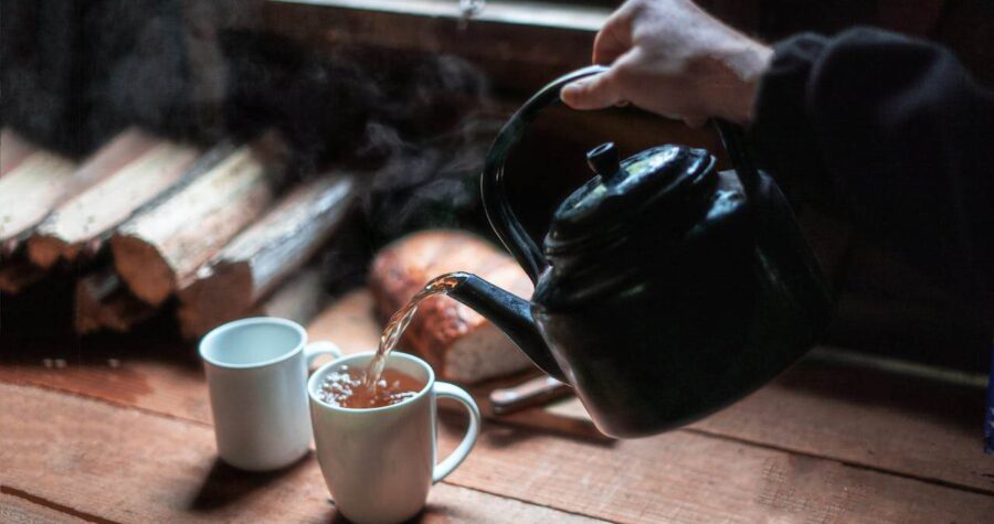 Person Pouring Tea In White Ceramic Mug