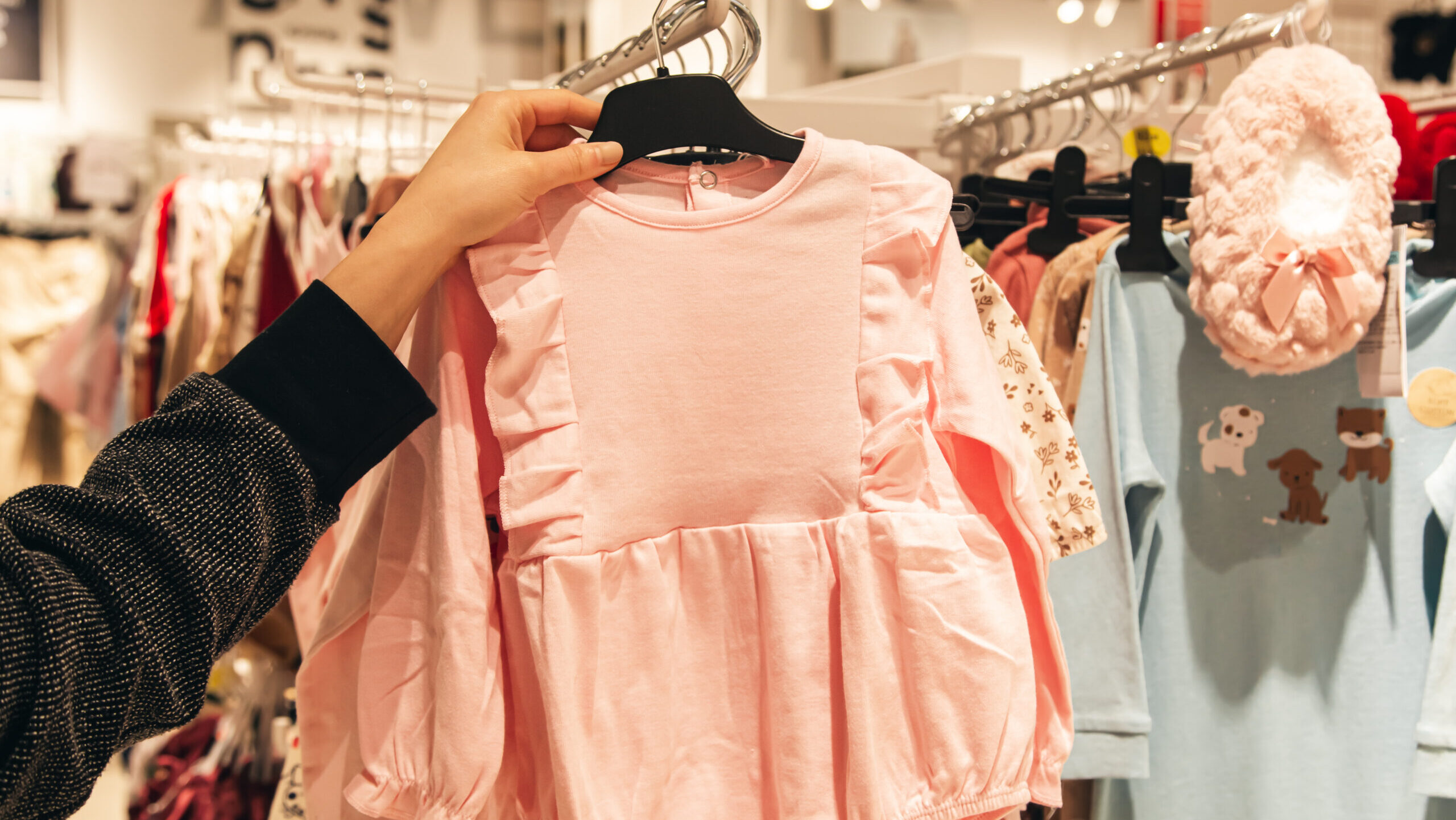 Little pink dress in baby store. Mother doing shopping in baby shop. Baby fashion, shopping time, sale and pregnancy concept.