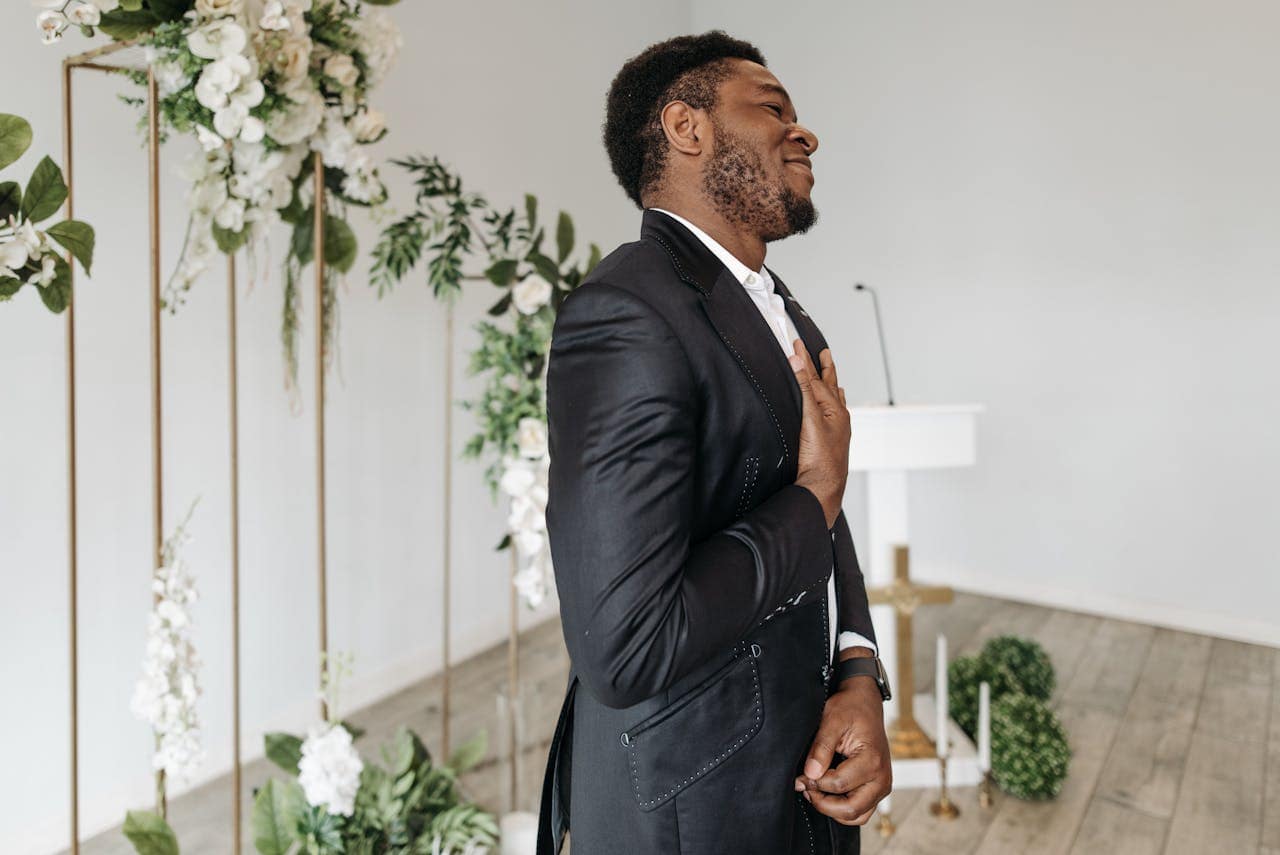 Happy Groom in Elegant Black Tuxedo Standing in a Church Hall