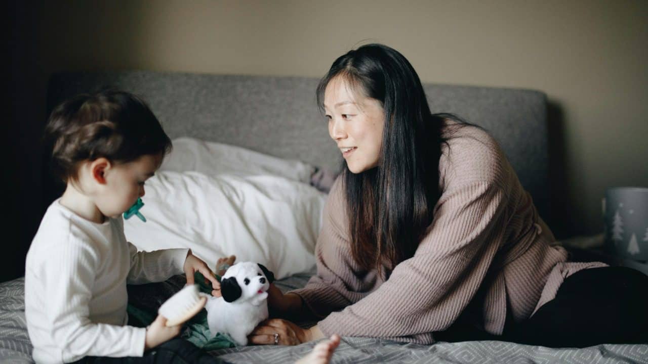 A heartwarming scene of a mother and child playing with toys on a bed. Captures the essence of family bonding.