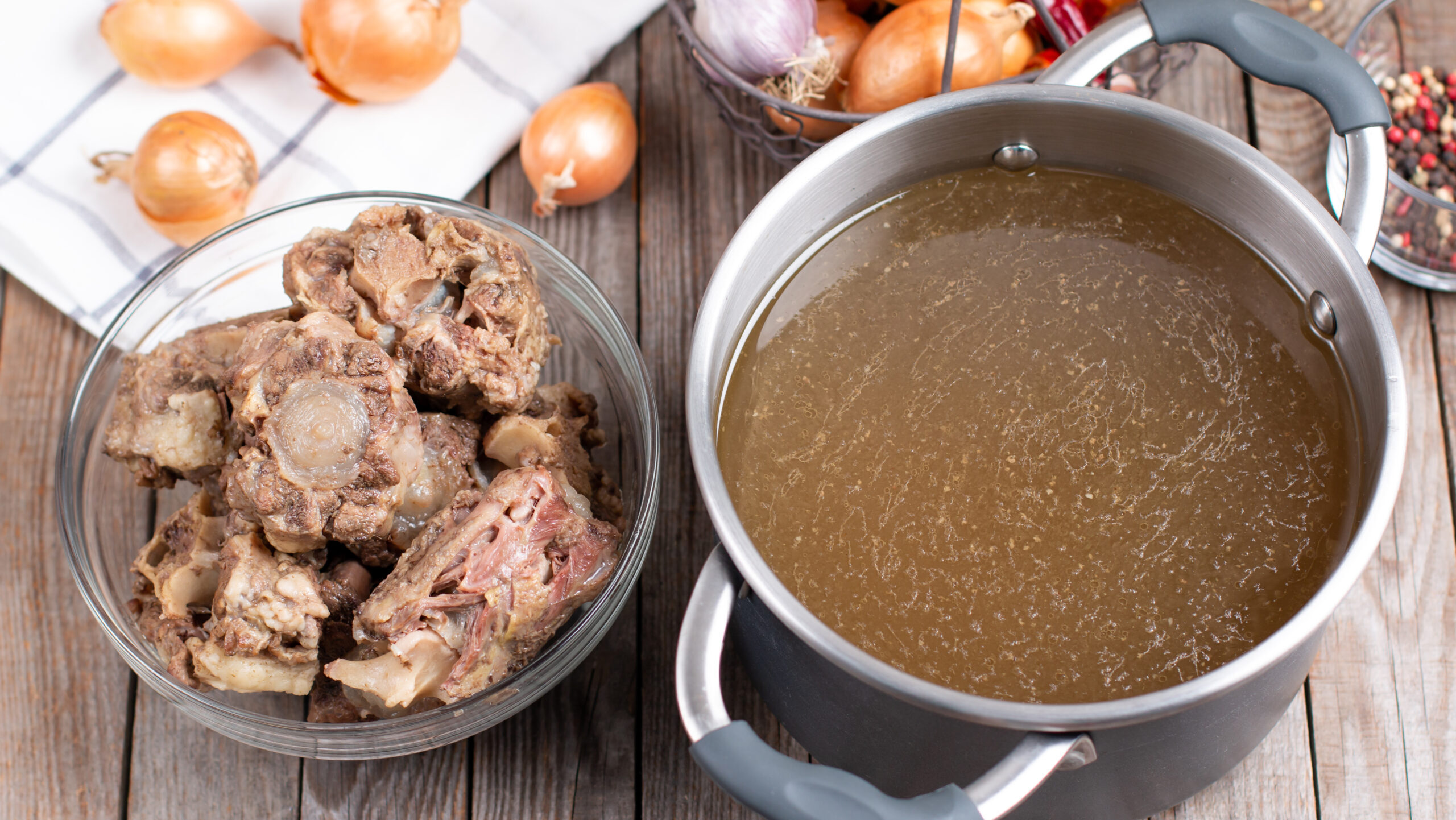 Bone Broth Bouillon in Metal saucepan on the wooden table, paleo diet